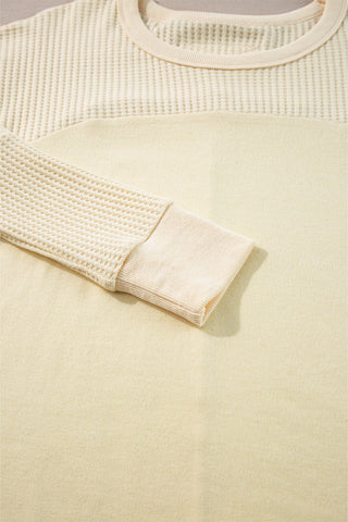 Close-up of a buttercup beige textured sweater with a focus on the sleeve and fabric texture.