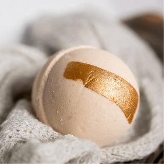 Bath bomb with gold accent on a textured surface